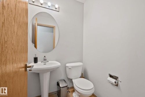 Pedestal sink with chrome fixtures and an oval mirror - 2819 33 Street Nw, Edmonton, AB - Indoor Photo Showing Bathroom