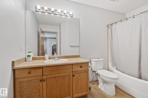 Bathroom featuring a wood-finish vanity with a beige countertop, an integrated sink, and a large wall-mounted mirror - 2819 33 Street Nw, Edmonton, AB - Indoor Photo Showing Bathroom