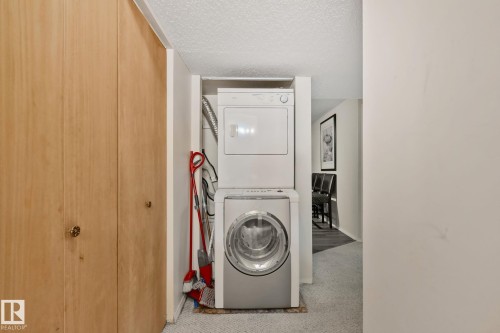 Dedicated laundry area featuring a stacked white dryer and a silver front-loading washing machine - 2819 33 Street Nw, Edmonton, AB - Indoor Photo Showing Laundry Room