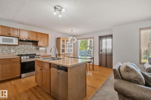 Open-concept kitchen featuring wood-finish cabinetry, stainless steel appliances, and a central island with integrated sink - 2819 33 Street Nw, Edmonton, AB - Indoor Photo Showing Kitchen With Double Sink