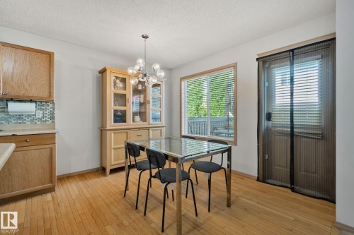 Dining area featuring wood-finish flooring, a contemporary chandelier, and a window with blinds - 2819 33 Street Nw, Edmonton, AB - Indoor