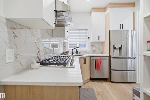 Modern kitchen with stainless steel appliances, light wood-finish flooring, and a white and wood-tone cabinetry scheme - 304 33 Avenue Nw, Edmonton, AB - Indoor Photo Showing Kitchen With Double Sink With Upgraded Kitchen