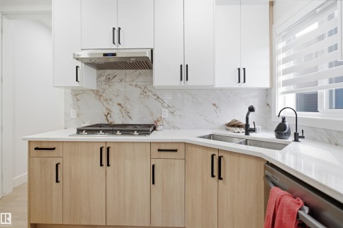Kitchen featuring two-tone cabinetry with light wood-finish base cabinets and white upper cabinets, complemented by matte black hardware - 304 33 Avenue Nw, Edmonton, AB - Indoor Photo Showing Kitchen With Double Sink With Upgraded Kitchen