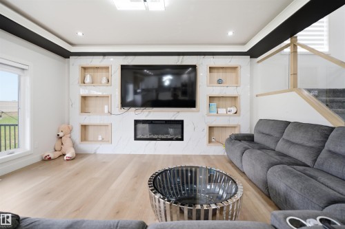 Contemporary living area featuring a white tiled accent wall with integrated shelving and a built-in electric fireplace - 304 33 Avenue Nw, Edmonton, AB - Indoor Photo Showing Living Room With Fireplace