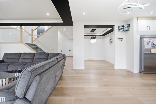 Light wood-finish flooring extending throughout, complemented by recessed lighting and a contemporary chandelier - 304 33 Avenue Nw, Edmonton, AB - Indoor