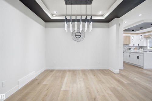 Recessed ceiling with black and white trim, wood-finish flooring, and a linear chandelier featuring crystal accents - 304 33 Avenue Nw, Edmonton, AB - Indoor