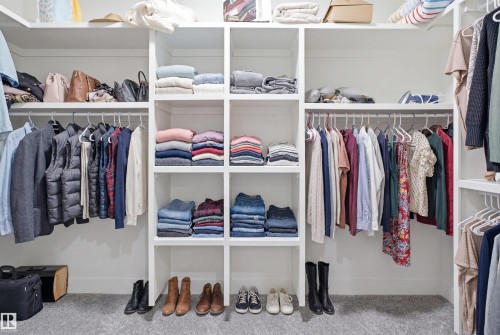 Built-in custom closet system featuring multiple hanging rods, open shelving, and a neutral carpeted floor - 304 33 Avenue Nw, Edmonton, AB - Indoor With Storage