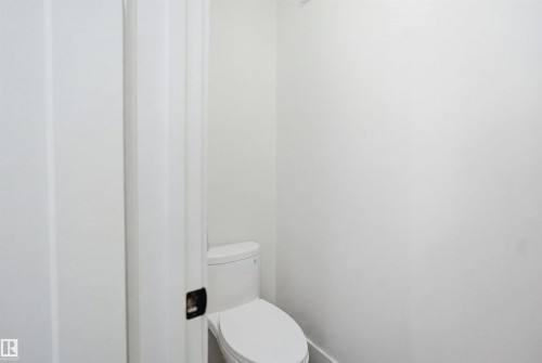 White water closet with a white toilet and a dark bronze door handle - 304 33 Avenue Nw, Edmonton, AB - Indoor Photo Showing Bathroom