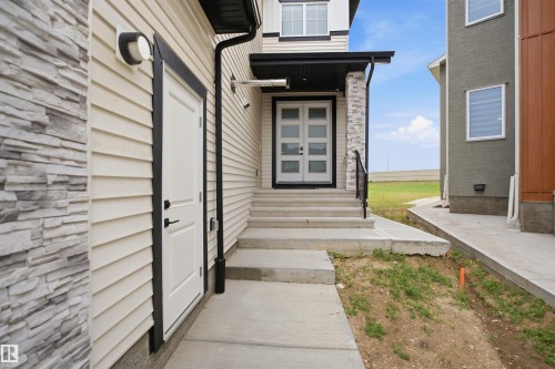 Contemporary entry featuring a multi-paneled double door, concrete steps, and a black metal handrail - 304 33 Avenue Nw, Edmonton, AB - Outdoor