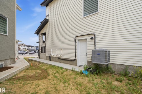 Cream-colored horizontal siding exterior featuring a white utility door and a ground-mounted HVAC unit - 304 33 Avenue Nw, Edmonton, AB - Outdoor With Exterior