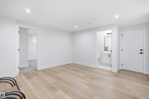 Spacious room featuring wood-finish flooring, recessed lighting, and white baseboards - 304 33 Avenue Nw, Edmonton, AB - Indoor Photo Showing Other Room
