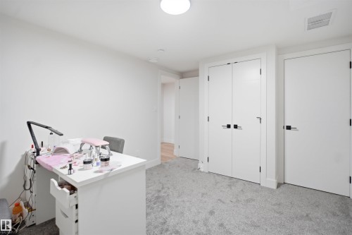 Spacious room featuring light gray carpeting, crisp white walls, recessed ceiling lighting, and multiple white panel doors with black hardware - 304 33 Avenue Nw, Edmonton, AB - Indoor Photo Showing Other Room