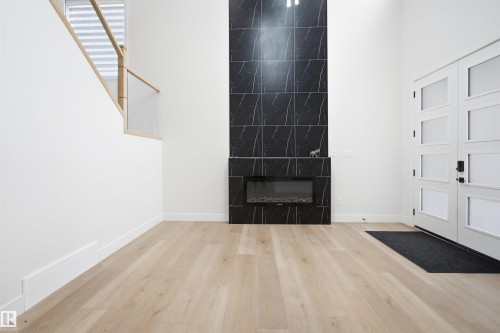 Spacious foyer featuring a floor-to-ceiling black marble-look tile fireplace surround with an electric insert - 304 33 Avenue Nw, Edmonton, AB - Indoor Photo Showing Other Room