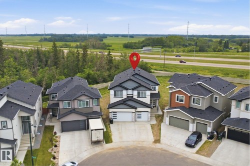 Two-story residence with a light and dark gray exterior, featuring a double garage with frosted glass panels, a paved driveway, and a dark shingle roof - 304 33 Avenue Nw, Edmonton, AB - Outdoor With Facade