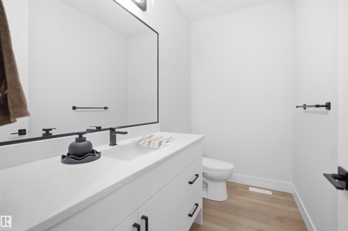 Modern bathroom featuring a single white vanity with a light-toned countertop, a black-framed mirror, and a black-finish faucet - 304 33 Avenue Nw, Edmonton, AB - Indoor Photo Showing Bathroom