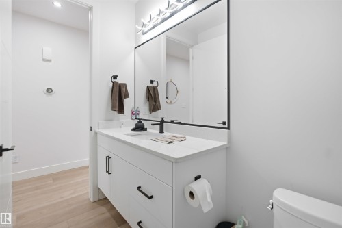 Bathroom featuring a white vanity with slab drawers, a white countertop, a rectangular undermount sink, and a black faucet - 304 33 Avenue Nw, Edmonton, AB - Indoor Photo Showing Bathroom