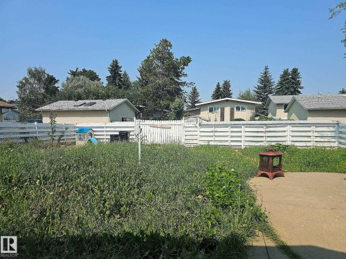 Fenced backyard with a concrete patio area and mature perimeter trees - 7812 144 Avenue Nw, Edmonton, AB - Outdoor