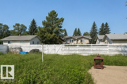 Expansive grassy area featuring a white horizontal plank fence with double gates - 7812 144 Avenue Nw, Edmonton, AB - Outdoor