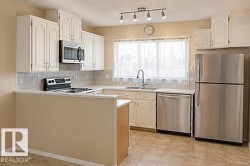Kitchen featuring white cabinetry, stainless steel appliances, a white tile backsplash, a window above the sink, and track lighting - 