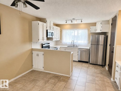 Kitchen featuring white cabinetry, tile flooring, stainless steel appliances, white countertops, and a ceiling fan - 7812 144 Avenue Nw, Edmonton, AB - Indoor Photo Showing Kitchen