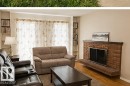 Living area featuring hardwood flooring, a brick fireplace with a floating hearth, and built-in shelving - 7812 144 Avenue Nw, Edmonton, AB  - Indoor Photo Showing Living Room With Fireplace 