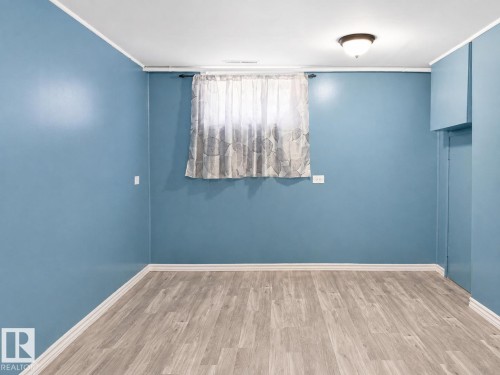 Room featuring wood-finish flooring, a window with curtains, and a ceiling-mounted light fixture - 7812 144 Avenue Nw, Edmonton, AB - Indoor Photo Showing Other Room