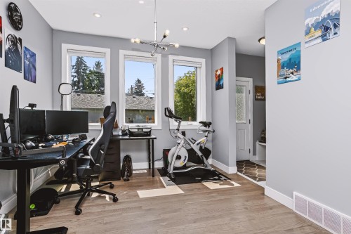 Room featuring light wood-finish flooring and three windows with white trim - 11305 79 Avenue Nw, Edmonton, AB - Indoor Photo Showing Office