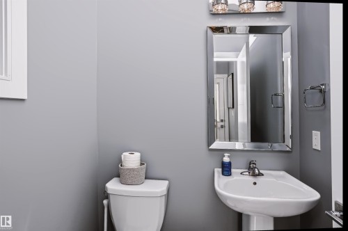 Pedestal sink with chrome faucet, framed vanity mirror, and overhead light fixture - 11305 79 Avenue Nw, Edmonton, AB - Indoor Photo Showing Bathroom