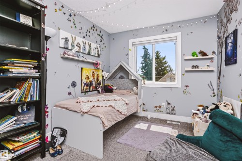 Spacious room featuring a large window, light gray walls, built-in shelving, and carpeted flooring - 11305 79 Avenue Nw, Edmonton, AB - Indoor Photo Showing Bedroom