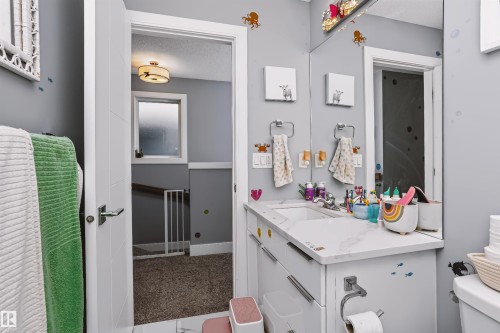 Bathroom vanity featuring a single basin, integrated countertop, full-width mirror, and overhead lighting - 11305 79 Avenue Nw, Edmonton, AB - Indoor Photo Showing Bathroom