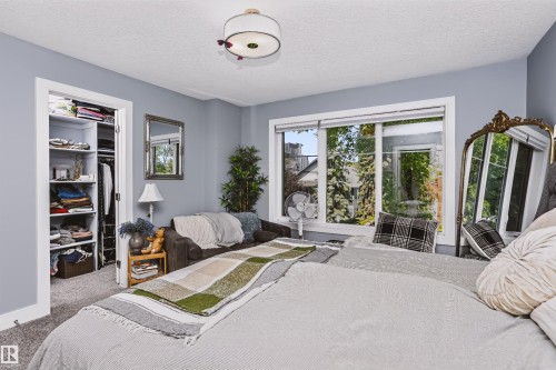 Light-filled room featuring a large window, built-in closet with shelving and hanging space, and a ceiling-mounted light fixture - 11305 79 Avenue Nw, Edmonton, AB - Indoor Photo Showing Bedroom