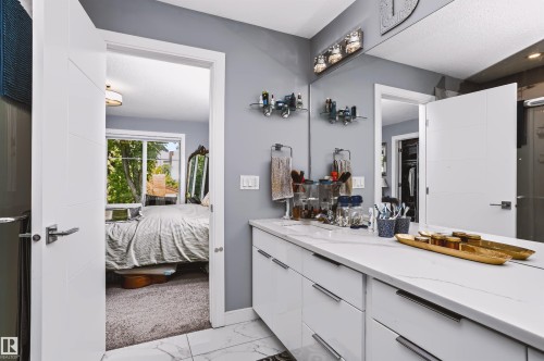 Contemporary vanity featuring a white countertop with integrated sink, modern cabinetry, and full-width mirror - 11305 79 Avenue Nw, Edmonton, AB - Indoor
