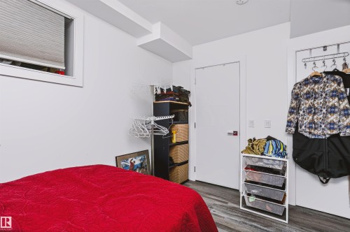 Room featuring a compact window with blinds, white walls, and wood-finish flooring - 11305 79 Avenue Nw, Edmonton, AB - Indoor Photo Showing Bedroom