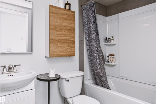 Contemporary bathroom featuring a pedestal sink with chrome faucet, white ceramic toilet, and sleek black round accent table - 11305 79 Avenue Nw, Edmonton, AB - Indoor Photo Showing Bathroom