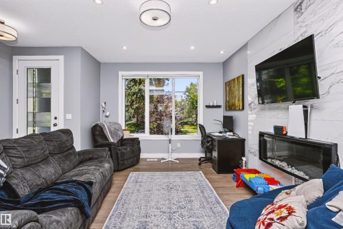 Living area with light gray walls, wood-finish flooring, recessed lighting, and a window offering abundant light - 11305 79 Avenue Nw, Edmonton, AB - Indoor Photo Showing Living Room With Fireplace