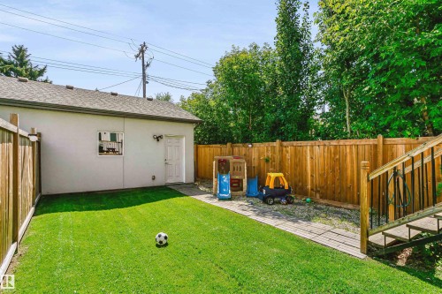 Expansive backyard featuring a manicured lawn, wood fencing, and a detached structure with an exterior door and window - 11305 79 Avenue Nw, Edmonton, AB - Outdoor With Backyard