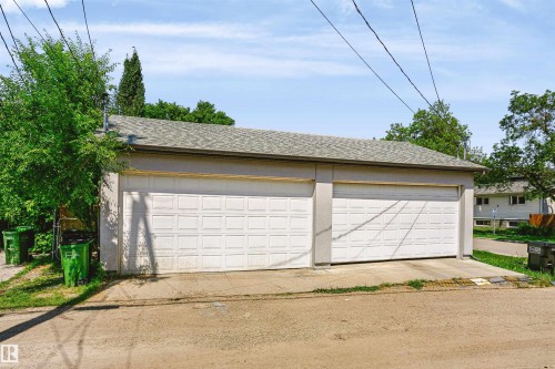 Detached two-car garage featuring panel-style garage doors, stucco siding, and a shingled roof - 11305 79 Avenue Nw, Edmonton, AB - Outdoor With Exterior