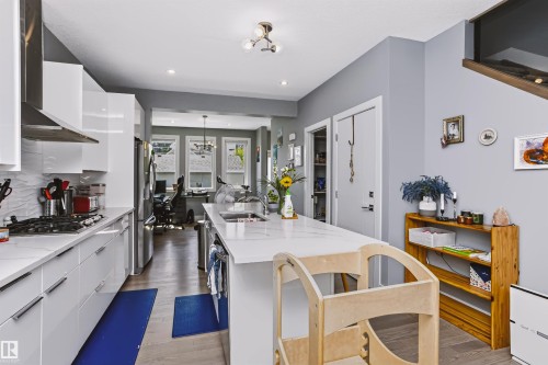 Modern kitchen featuring white glossy cabinetry, a built-in gas range, and a large central island with an integrated sink - 11305 79 Avenue Nw, Edmonton, AB - Indoor Photo Showing Kitchen With Upgraded Kitchen