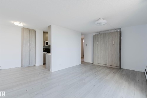 Spacious open-concept living area showcasing light wood-finish flooring, clean white walls, and abundant natural lighting - #303 10883 Saskatchewan Dr Nw, Edmonton, AB - Indoor Photo Showing Other Room