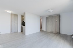 Spacious open-concept living area showcasing light wood-finish flooring, clean white walls, and abundant natural lighting - 