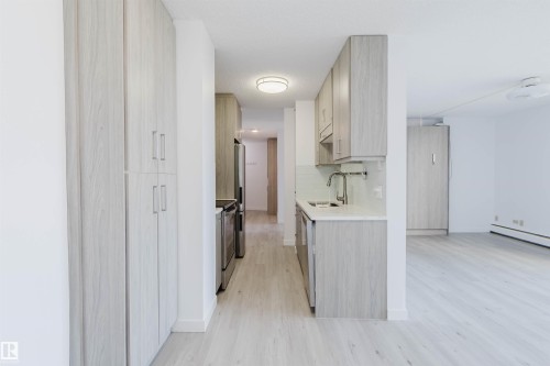 Galley kitchen featuring light wood-finish cabinetry, stainless steel appliances, and a light-toned countertop - #303 10883 Saskatchewan Dr Nw, Edmonton, AB - Indoor