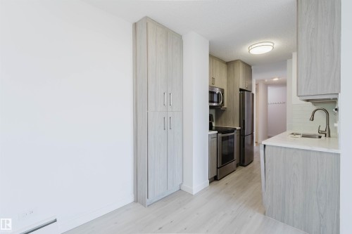 Galley kitchen featuring light wood-finish cabinetry, stainless steel appliances, white countertops, and a subway tile backsplash - #303 10883 Saskatchewan Dr Nw, Edmonton, AB - Indoor Photo Showing Kitchen