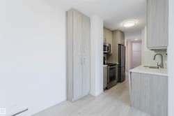 Galley kitchen featuring light wood-finish cabinetry, stainless steel appliances, white countertops, and a subway tile backsplash - 
