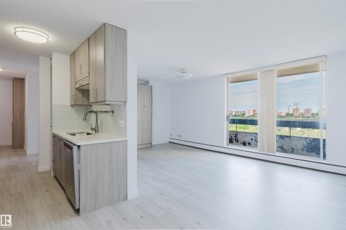 Open-concept living space featuring wood-finish flooring, a contemporary kitchen with light wood-finish cabinetry, stainless steel appliances, and a light countertop - #303 10883 Saskatchewan Dr Nw, Edmonton, AB - Indoor Photo Showing Kitchen