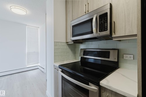 Contemporary kitchen with wood-finish cabinetry, stainless steel appliances, and a light-toned countertop - #303 10883 Saskatchewan Dr Nw, Edmonton, AB - Indoor Photo Showing Kitchen