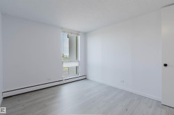 Bright room featuring a large window, light-toned wood-finish flooring, white walls, and a white door with a black knob - 