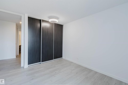 Minimalist room featuring light wood-finish flooring and a contemporary flush-mount ceiling light - #303 10883 Saskatchewan Dr Nw, Edmonton, AB - Indoor Photo Showing Other Room