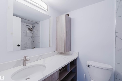 Bathroom featuring a single vanity with an integrated sink, brushed nickel faucet, and a large wall-mounted mirror - #303 10883 Saskatchewan Dr Nw, Edmonton, AB - Indoor Photo Showing Bathroom