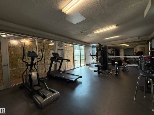 Spacious fitness room featuring a full wall of mirrors and durable rubber flooring - #303 10883 Saskatchewan Dr Nw, Edmonton, AB - Indoor Photo Showing Gym Room