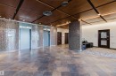 Spacious lobby featuring large format floor tiles, an elevator bank with textured wall finishes, and a wood-panel ceiling with integrated lighting - #303 10883 Saskatchewan Dr Nw, Edmonton, AB  - Indoor Photo Showing Other Room 
